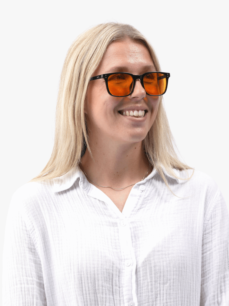 Kvinna i vit skjorta bär Obsidian 90 Black svarta glasögon med orange linser, leende