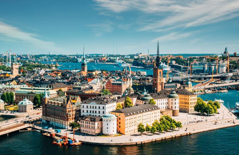Flygfoto över Stockholms innerstad och vatten, Gamla stan med Riddarholmskyrkans spetsiga torn i solsken